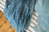 Indigo-dyed African textile with ivory patterns, zigzag stitching, and fringed edge.