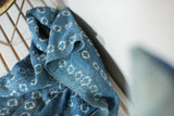 Intricate ivory circle patterns and hand-stitched lines on a vintage African indigo textile.