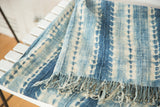 Folded vintage African indigo textile, with hand-woven texture, unique blue and ivory pattern, and short fringe.