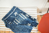 Folded African indigo textile featuring unique ivory patterns and hand-woven texture.