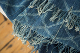 Hand woven vintage African indigo textile detail with light blue pattern and long frayed tassels.