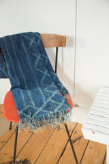 Vintage hand-woven indigo textile with light blue geometric pattern and long tassels.