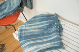 Hand-woven African indigo textile with intricate denim blue and ivory striped patterns.