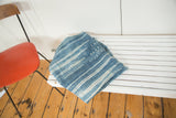 Folded African indigo throw, hand-woven denim blue and ivory stripes with unique stitched details.