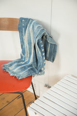 Hand-woven African textile's frayed edge with unique indigo and ivory stripe pattern.
