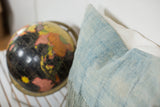Vintage African indigo pillow featuring sun-faded texture, stitched lines, and long tassels.