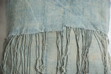 Frayed long tassels and subtle texture on a sun-faded light blue indigo pillow.