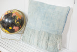 Sun-faded light blue vintage African Indigo pillow with long tassels, 22x22 inches.