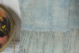 Close-up of a sun-faded vintage African indigo textile pillow with long tassels.