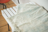 Supple hand-woven African indigo textile showing faded ivory and powder blue stripes with fringe.