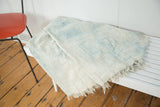 Powder blue and ivory African indigo textile displaying hand-stitched detailing and fringed edge.