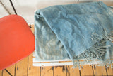 Hand woven vintage African indigo textile throw, displaying varied powder blue tones and fringe.