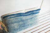 Upper portion of the vintage indigo pillow, showing sun-faded blue textile and ivory linen edge.