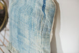 Close-up of sun-faded light blue indigo textile, highlighting its hand-woven texture and side seam.