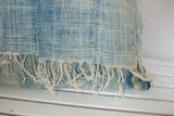 Vintage African Indigo pillow with sun-faded light blue textile and frayed short tassels.