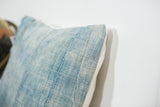 Detail of vintage sun-faded light blue indigo pillow showing textured fabric and stitched seam.