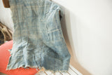Supple, hand-woven denim blue African indigo textile with subtle vertical seams and frayed edges.