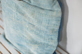 Sun-faded light blue African indigo textile pillow with varied texture.