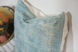 Sun-faded light blue indigo textile texture with white canvas backing.