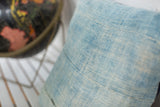 Close-up of light blue indigo pillow, highlighting sun-faded color and reclaimed textile texture.