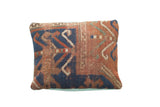 Antique Kazak rug fragment pillow with bold geometric patterns in indigo and terracotta.