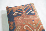 Worn antique Kazak rug fragment pillow, geometric blue-rust pattern, faded turquoise linen back.