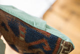 Detail of rich blue and orange hand-knotted antique Kazak rug fragment and faded turquoise linen.