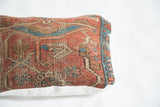 Antique Heriz rug fragment pillow, angled view showing softened red, blue geometric border.