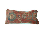 Aged red Heriz Persian rug fragment pillow showcasing tribal patterns and mint green linen.