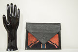 Bold red and black Oushak rug fragment clutch with textured black leather flap.