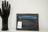 Textured black leather clutch corner, bright blue zipper, brand tag.