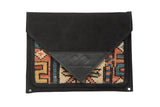 Handmade clutch with a black suede envelope flap and a colorful antique geometric rug fragment.