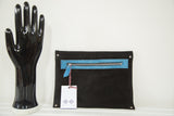 The back of the handmade clutch in black vegetable suede with a blue zipper pocket.