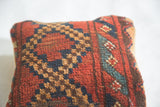 Storied texture of antique Afghani rug fragment pillow with geometric red, blue, and brown diamonds.