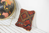 Geometric diamond pattern with rich red, blue, gold tones on an antique Afghani rug pillow.