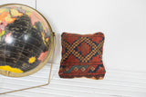 Antique Afghani rug fragment pillow with geometric deep red, blue, and gold diamond pattern.