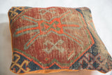 Geometric pattern and worn texture of the antique Caucasian pillow in red, blue, and tangerine velvet.