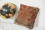 Geometric antique Caucasian rug fragment pillow, natural wear, visible tangerine velvet side.