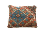 Antique Caucasian rug fragment pillow displaying geometric faded red and blue patterns.