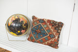 Collectible hand-knotted antique Caucasian rug fragment pillow, faded red and blue geometric medallion.