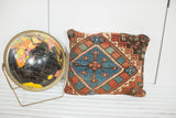 Geometric pattern detail with faded red and blue tones on the antique Caucasian pillow.