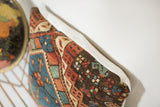 Textured Caucasian rug fragment pillow, faded red and blue geometric patterns, white linen.
