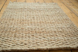 Tightly woven hand-braided texture of the ivory natural fiber entrance mat.