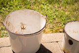 Cream vintage enamel pail with handle, showing heavy internal rust and chippy enamel.