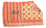 Vibrant hand-stitched Kantha quilt showing red stripes, cream diamonds, and a blue patch.