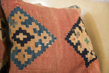 Faded terracotta and indigo geometric pattern on an early 20th century Kilim pillow fragment.