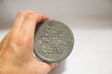 Aged gray zinc lid of the antique Ball Jelly Glass candle, embossed with script.