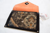Handmade rug clutch opened to reveal its bright orange suede lining and magnetic snap.