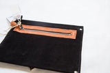 Exterior zipper pocket with tan trim on the black suede back of the handmade clutch.