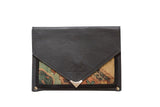 Closed view of a handmade clutch with a dark suede flap and polished metal V-clasp.